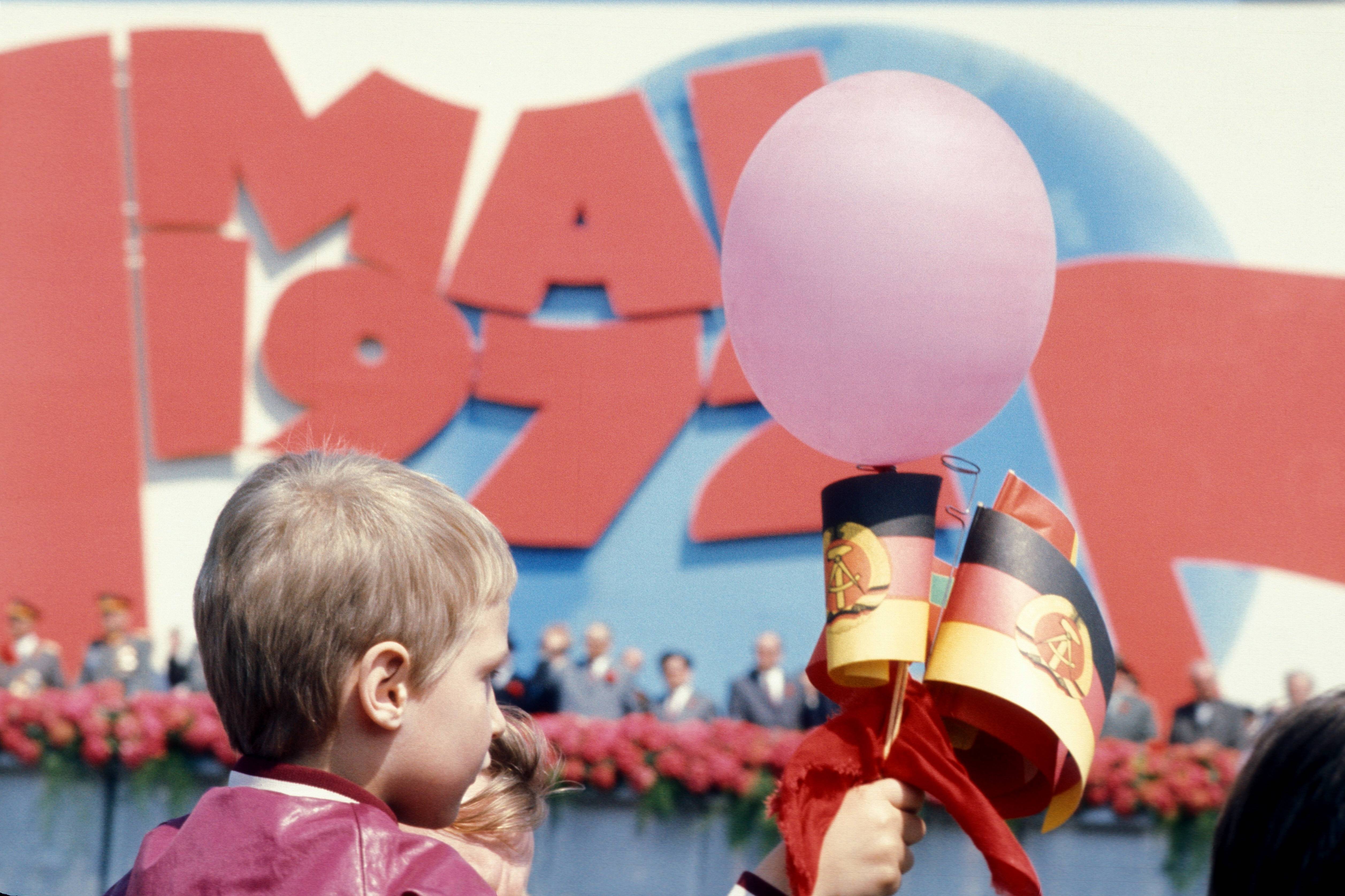 IMAGO / Sven Simon | Boy with a balloon and GDR flags in the May Day demonstration in East Berlin. 1 May 1972, Berlin.